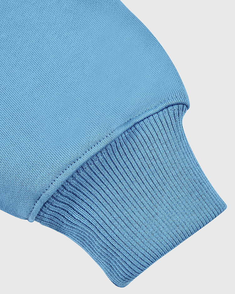 Close-up of the Ebbets Field University of North Carolina Heavyweight Cotton Terry Pullover Hoodie in blue, highlighting the ribbed cuff and smooth French terry fabric texture on the sleeve.