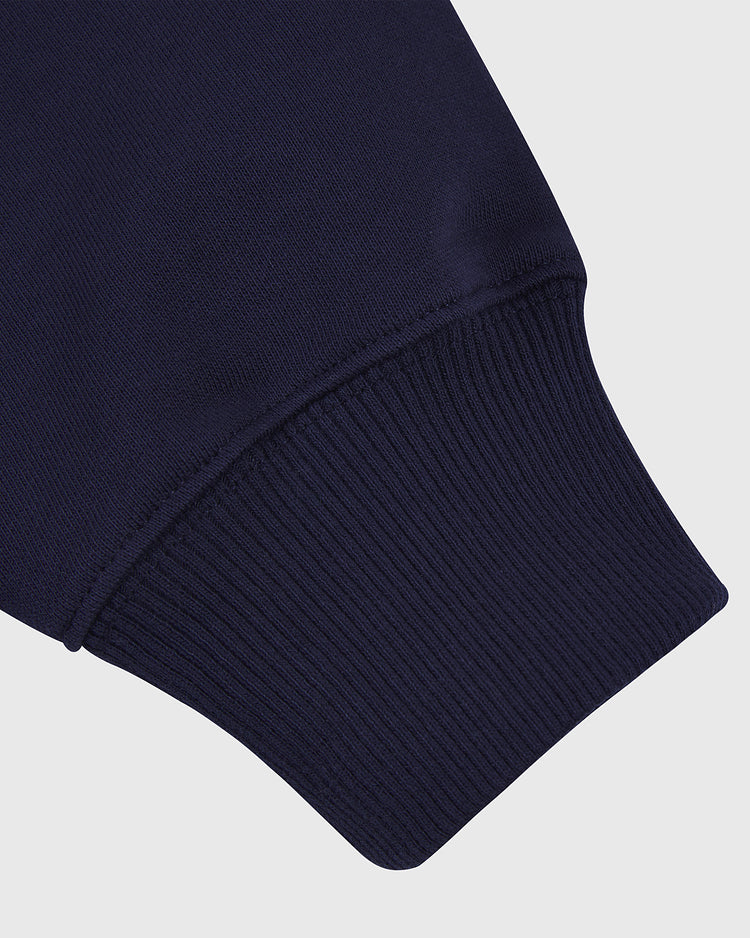 Close-up of the MICHIGAN HOODIE NAVY by Ebbets Field, highlighting the ribbed cuff and smooth navy fabric sleeve against a plain light background.