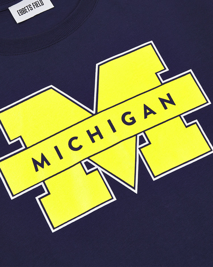 The Ebbets Field MICHIGAN SS TEE NAVY features a large yellow block M and bold MICHIGAN lettering across the front, with an Ebbets Field label at the neckline.