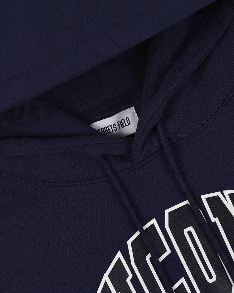 Close-up of the UCONN HOODIE NAVY by Ebbets Field, highlighting the navy hood, drawstrings, part of a white print, and an inner label reading Ebbets Field.
