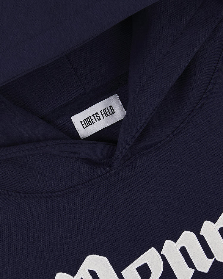 Close-up of the Ebbets Field PENN STATE HOODIE NAVY featuring a white Ebbets Field label sewn inside the neckline and a partial view of a white design on the front.