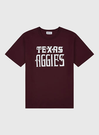 The Ebbets Field TEXAS A&M SS TEE MAROON features bold white TEXAS AGGIES text in a stylized font on the front and is displayed flat on a light gray background.