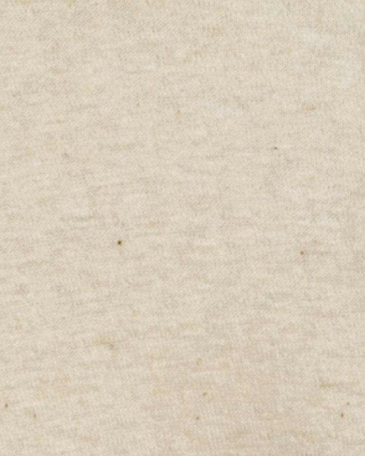 A close-up of the soft, beige fabric of the EFF Fungo Shirt - Red Sleeves, featuring a subtly textured surface with small dark specks, inspired by classic vintage wool blend baseball uniform undershirts.