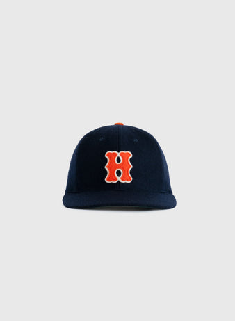 The Hiroshima Carp 1958 Authentic Wool Ballcap by Ebbets Field Flannels features a navy blue design with a bold orange and white “H” on the front, authentically reproducing the classic style, shown against a plain light gray background.