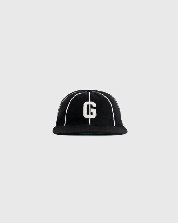 A black baseball cap with white vertical stripes and a large white letter G embroidered on the front, shown against a plain gray background.