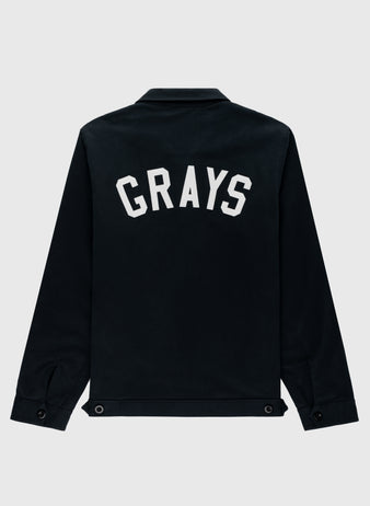 The Ebbets Field Flannels Homestead Grays Cotton Grounds Crew Jacket is a black cotton twill jacket featuring “GRAYS” in bold white letters across the upper back, inspired by the historic Homestead Grays, shown on a light gray background.