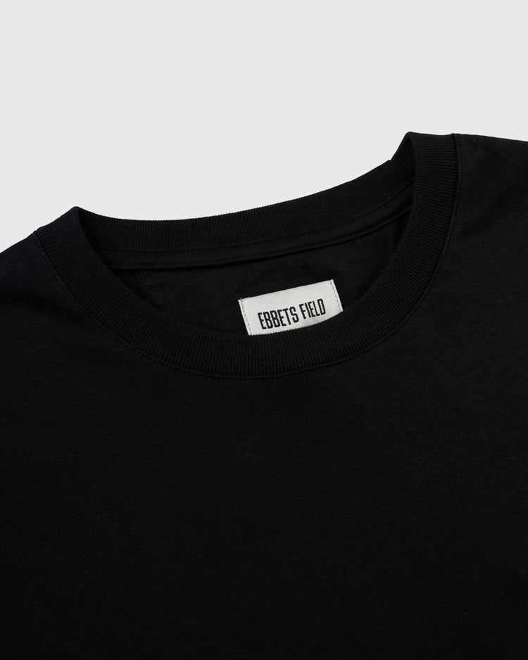 A close-up of the Homestead Grays Embroidered G Long Sleeve Pocket Tee by Ebbets Field Flannels, featuring a visible inside collar label and set against a light gray background.