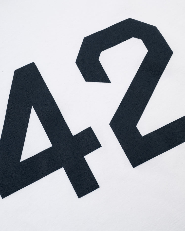 A close-up of the black number 42 printed on a white Jackie Robinson 42 Vintage Baseball Tee by Ebbets Field.