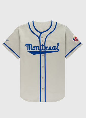 The Ebbets Field Montreal Royals Cotton Twill Baseball Jersey features gray fabric, blue trim and buttons, Montreal in blue script on the chest, and a left-sleeve patch with red and gold accents inspired by Jackie Robinson.