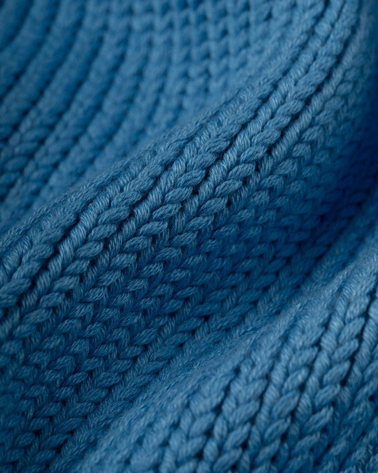 Close-up of textured blue wool from the Montreal Expos 1969 Shawl Collar Sweater by Ebbets Field Flannels, highlighting tightly woven stitches and soft, curved ridges reminiscent of vintage athletic designs.