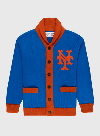 The Ebbets Field Flannels New York Mets 1962 Wool Shawl Collar Sweater features blue wool with orange trim, buttons, pockets, and a bold NY chest logo. This replica baseball sweater is displayed on a plain light background.