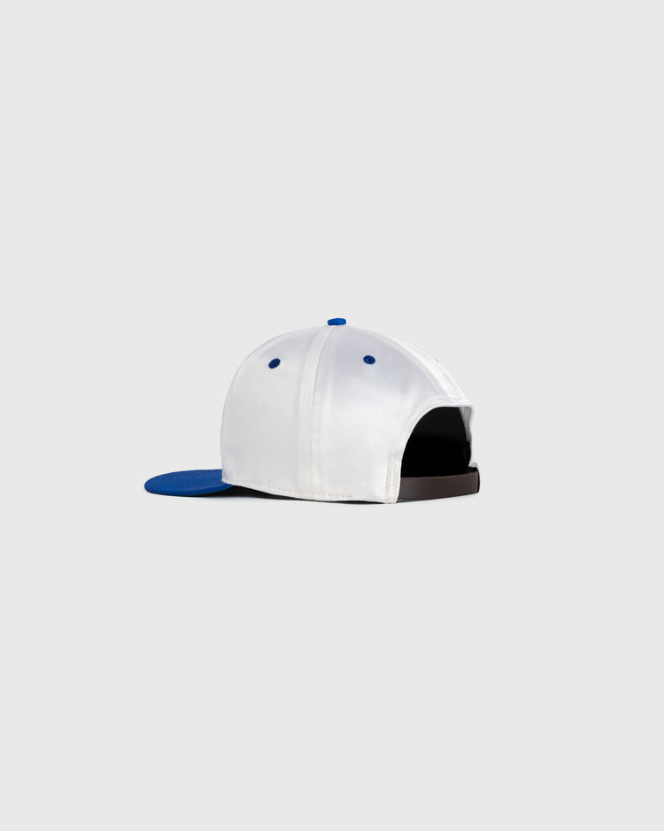 The EFF Montreal Royals 1946 Authentic All Satin Ballcap is white with a blue brim and accents, shown from the back. It features an adjustable strap and metal eyelets for ventilation, set against a plain light gray background.