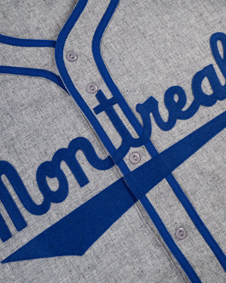 Close-up of the Ebbets Field Montreal Royals 1946 Authentic Wool Road Baseball Jersey in gray with blue trim, featuring Montreal in script—a replica honoring Jackie Robinson’s historic season.