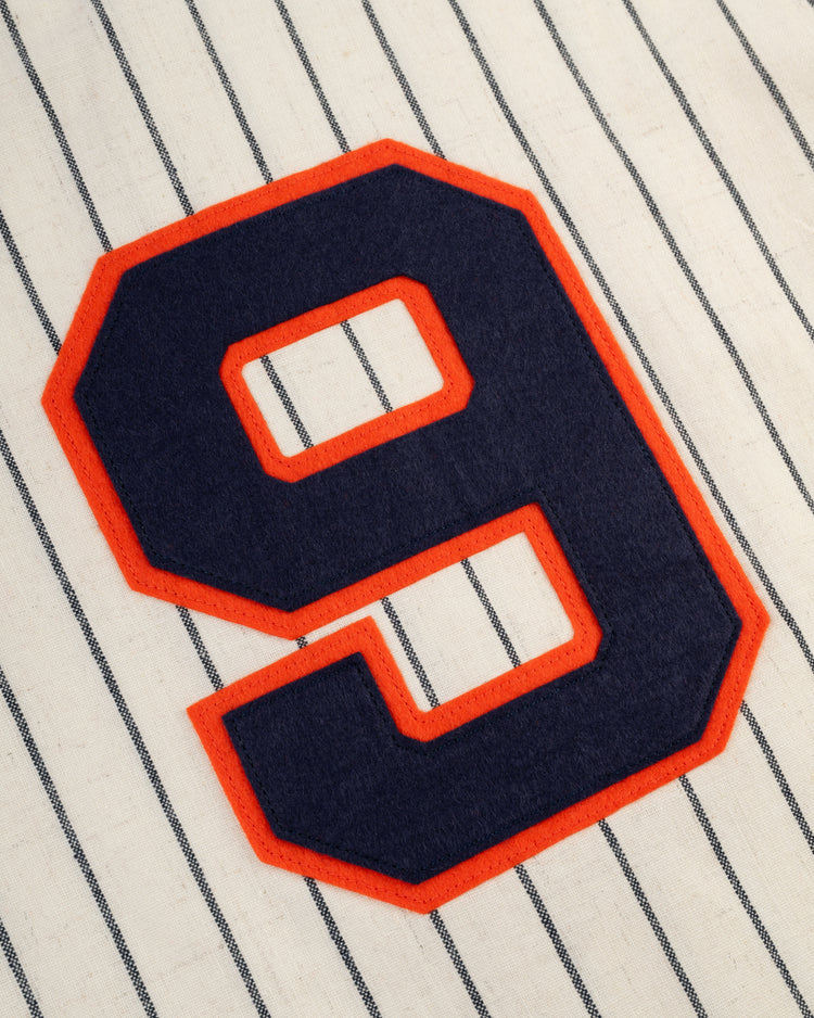 A large navy blue number 9 outlined in red is sewn on white fabric with black pinstripes, just like the iconic Ebbets Field New York Knights 1939 Authentic Wool Home Baseball Jersey from The Natural.