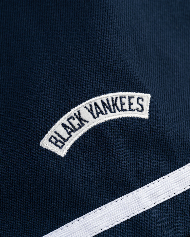 Close-up of the Ebbets Field New York Black Yankees Cotton Twill Baseball Jersey, featuring a white embroidered “BLACK YANKEES” patch and diagonal stripe—a tribute to the Negro Leagues baseball legacy.