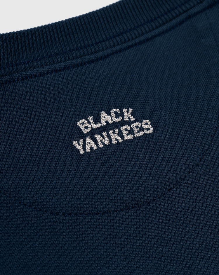 Close-up of the Ebbets Field New York Black Yankees Embroidered NY Short Sleeve Tee in dark blue, featuring white NY embroidery near the neckline to honor the Negro National League.