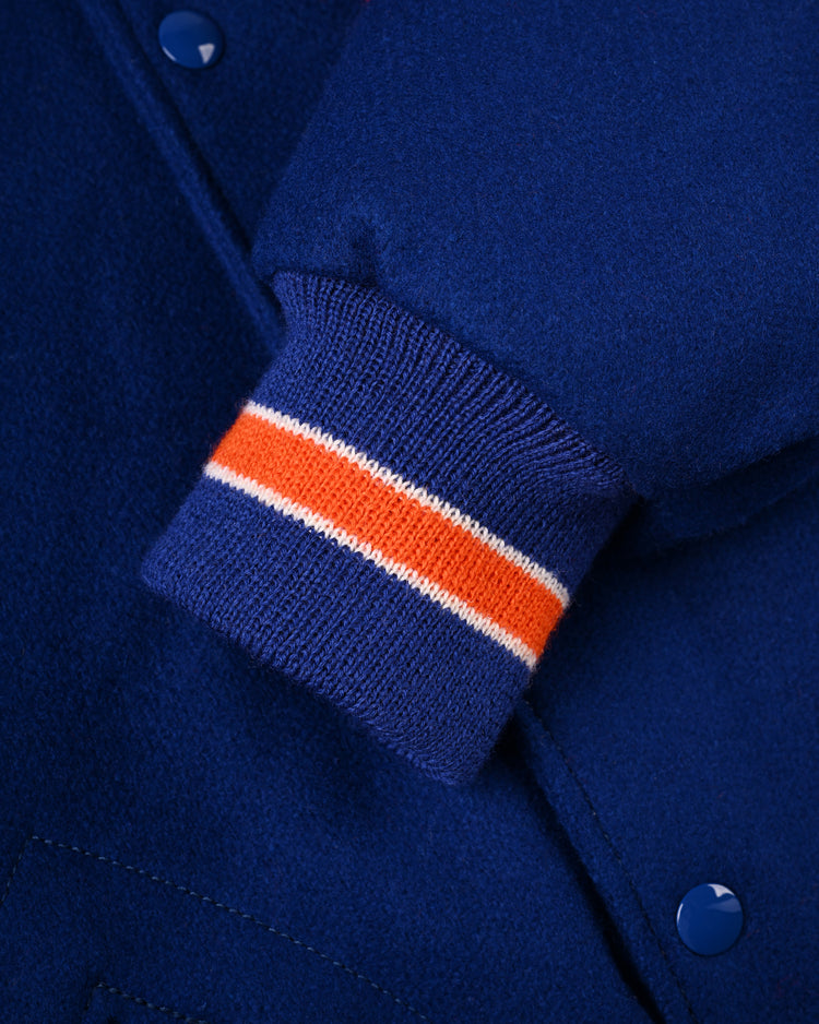 Close-up of the New York Mets 1969 Authentic All Wool Varsity Jacket by EFF, highlighting a sleeve with ribbed cuff in orange and white stripes, blue snap buttons, and textured fabric—an authentic tribute to classic World Series style.