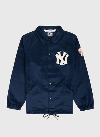 The EFF New York Yankees 1946 Satin Windbreaker Jacket is navy blue with a collar, elastic cuffs, drawstring hem, a large white Yankees logo on the left chest, and a circular Yankees patch on the sleeve.