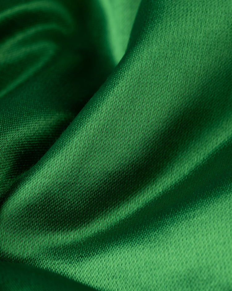 Close-up of smooth, shiny green satin with gentle folds and a silky sheen, capturing the look of the EFF Oakland Athletics 1968 Authentic All Satin Varsity Jacket.