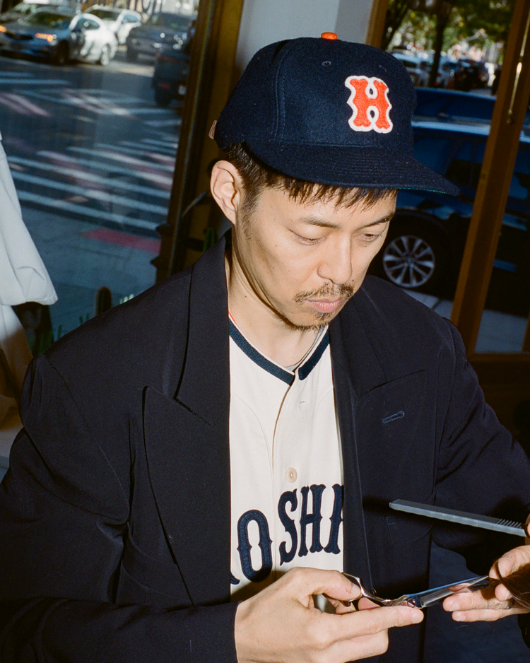 Man wearing a Hiroshima Carp wool ball cap in front of a window