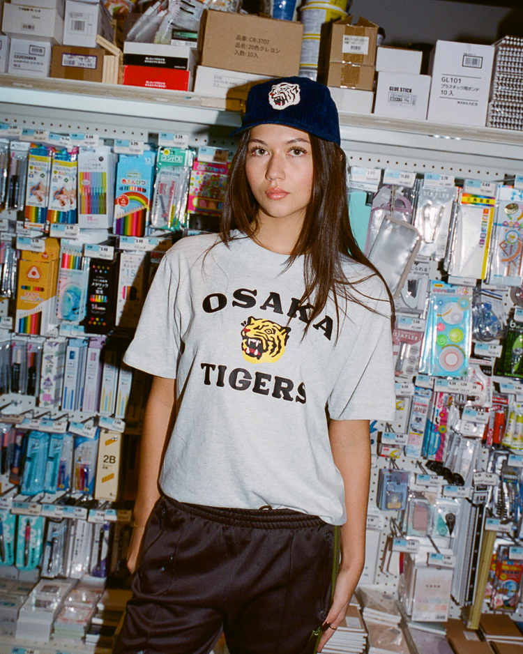 Person wearing a 'Osaka Tigers' shirt in a store with stationery items.