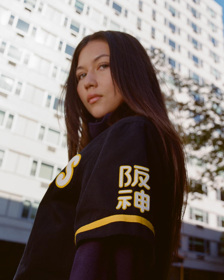 Woman wearing a black Tigers jersey with yellow text in an urban setting