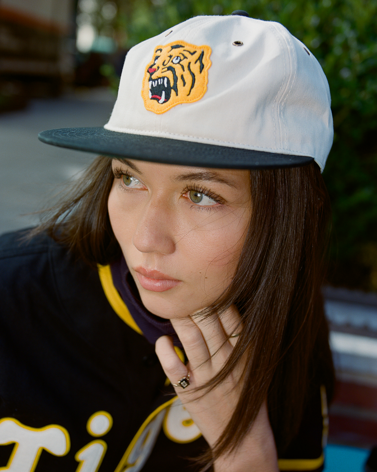 Person wearing a white cotton twill cap with an Osaka Tigers logo and a black Osaka Tigers jersey.