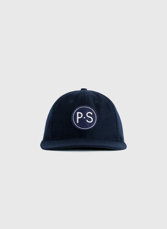The EFF Penn State University 1963 Authentic Wool Ballcap is a navy cap with a curved brim and a white embroidered circle featuring P.S, inspired by vintage Nittany Lions logo style. Plain light gray background.