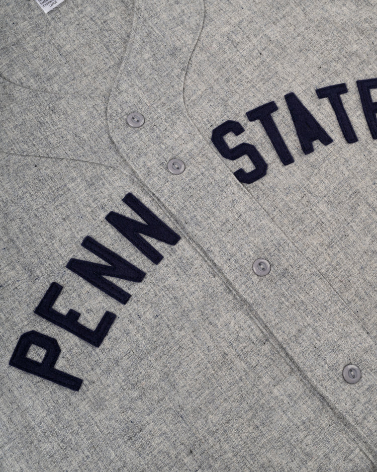 A close-up of the Ebbets Field Penn State University 1955 Authentic Wool Road Baseball Jersey, featuring PENN STATE in bold navy letters on gray wool, inspired by the classic design.