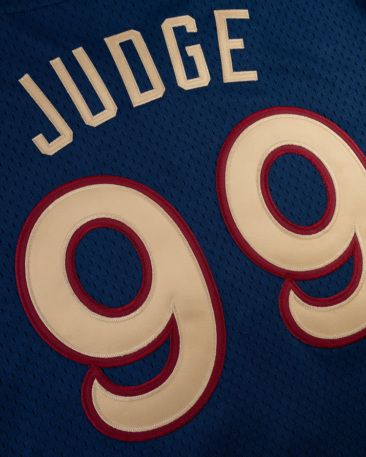 Close-up of the Ebbets Field AARON JUDGE BUTTON UP MESH JERSEY in navy, showcasing JUDGE in white and the number 99 in large cream digits outlined in red.