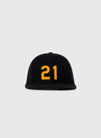 The Ebbets Field Flannels Roberto Clemente 1972 Signature Series Wool Ballcap, featuring a yellow number 21 on the front, is displayed against a plain light gray background.