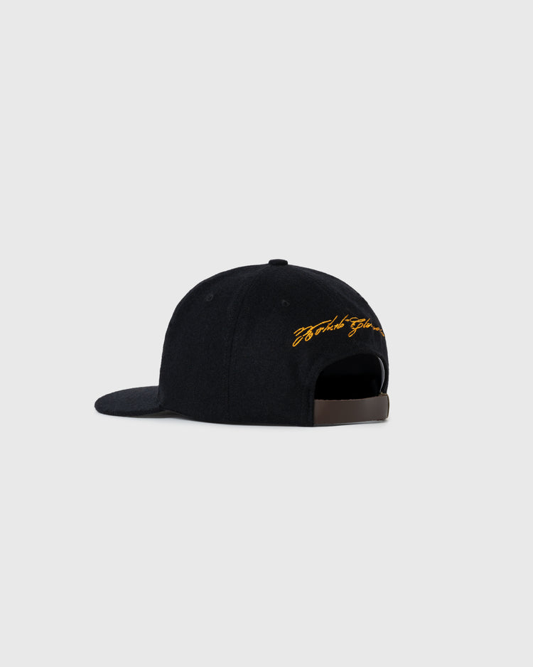 The Ebbets Field Flannels Roberto Clemente 1972 Signature Series Wool Ballcap is shown from the back, with yellow cursive embroidery above its brown adjustable strap, set against a plain light gray background.