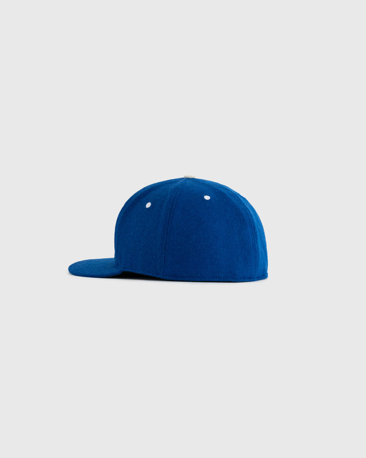 The Santurce Cangrejeros 1954 Authentic Wool Ballcap by EFF, shown in blue with a flat brim and white eyelets on a light gray background, pays tribute to the iconic cap worn by Roberto Clemente.
