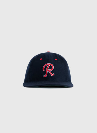 The EFF Seattle Rainiers 1957 Authentic Wool Ballcap features a navy blue design with a red and white embroidered R on the front, inspired by the 1957 team, shown against a plain light gray background.