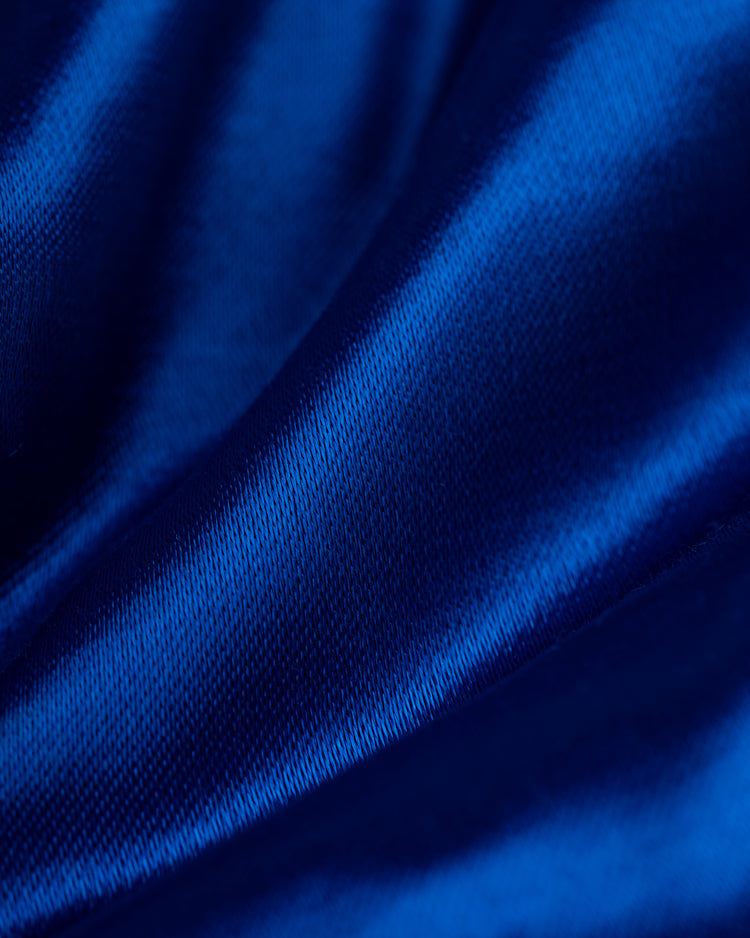 Close-up of smooth, shiny blue satin fabric with soft folds and highlights from the EFF Seattle Mariners 1982 Authentic All Satin Varsity Jacket, showcasing its silky texture and vibrant color.