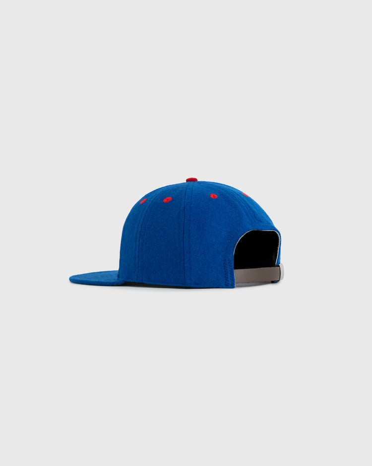 The EFF Seattle Rainiers 1938 Authentic 8-Panel Wool Ballcap, in blue with red eyelets and top button, features an adjustable black strap. Shown from the back/side on a light gray background.