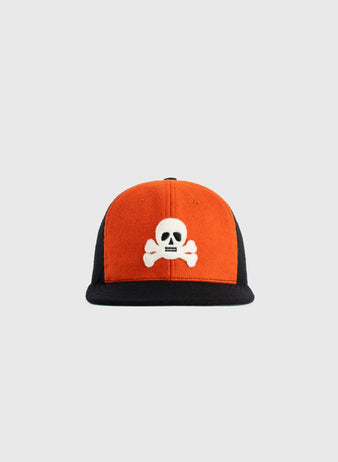 The EFF Sioux City Ghosts 1935 Authentic Wool Softbrim Ballcap features an orange front, black sides and brim, and a white skull and crossbones embroidered on the front, inspired by the legendary Negro League teams design.