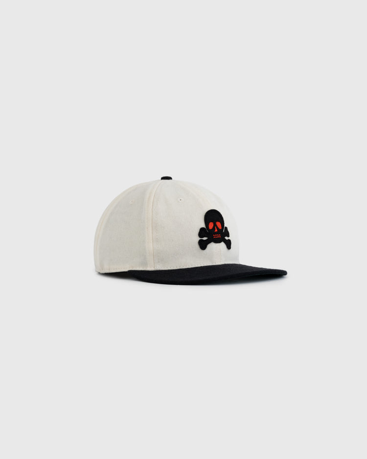 The EFF Sioux City Ghosts Two Tone Vintage Inspired Wool Ballcap features a white crown, black brim, and a black skull and crossbones with red eyes on the front, channeling 1935 baseball style. Displayed on a light gray background.