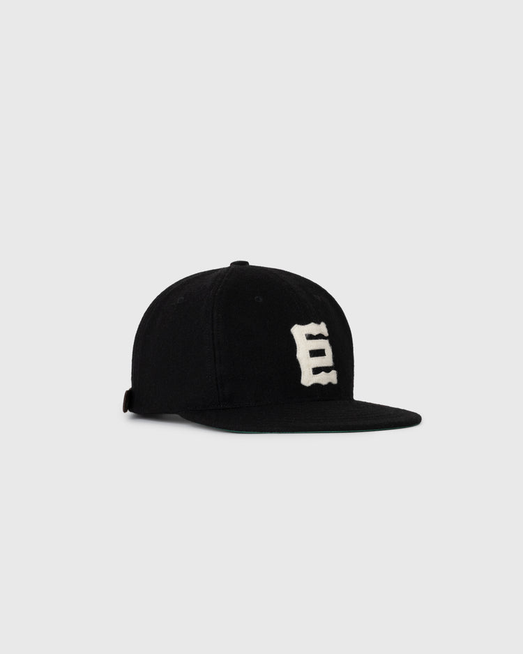 The Ebbets Field NEW - Tokyo Kyojin (Giants) 1940 Vintage Ballcap, a black flat-brim cap with a bold white E on the front, is displayed against a plain light gray background.