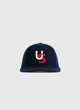 The US All-Stars 1957 Authentic Wool Ballcap by Ebbets Field Flannels features navy wool with white and red interlocking U and S embroidery, replicating the classic look of the 1957 team cap against a light gray background.