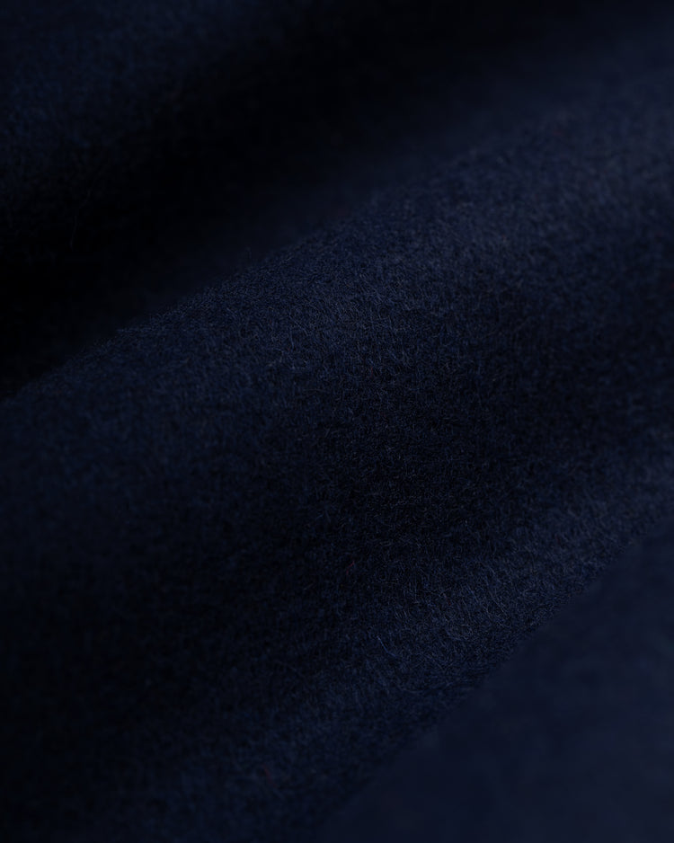 A close-up of dark navy blue wool fabric from the EFF University of Notre Dame Authentic Wool & Leather Varsity Jacket, featuring a soft, slightly textured surface with gentle folds that create subtle shadows and highlights.