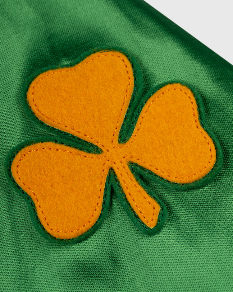 A yellow felt shamrock with three heart-shaped leaves is sewn onto shiny green fabric on the EFF University of Notre Dame Satin Windbreaker Jacket, adding a classic, vintage-inspired collegiate touch.