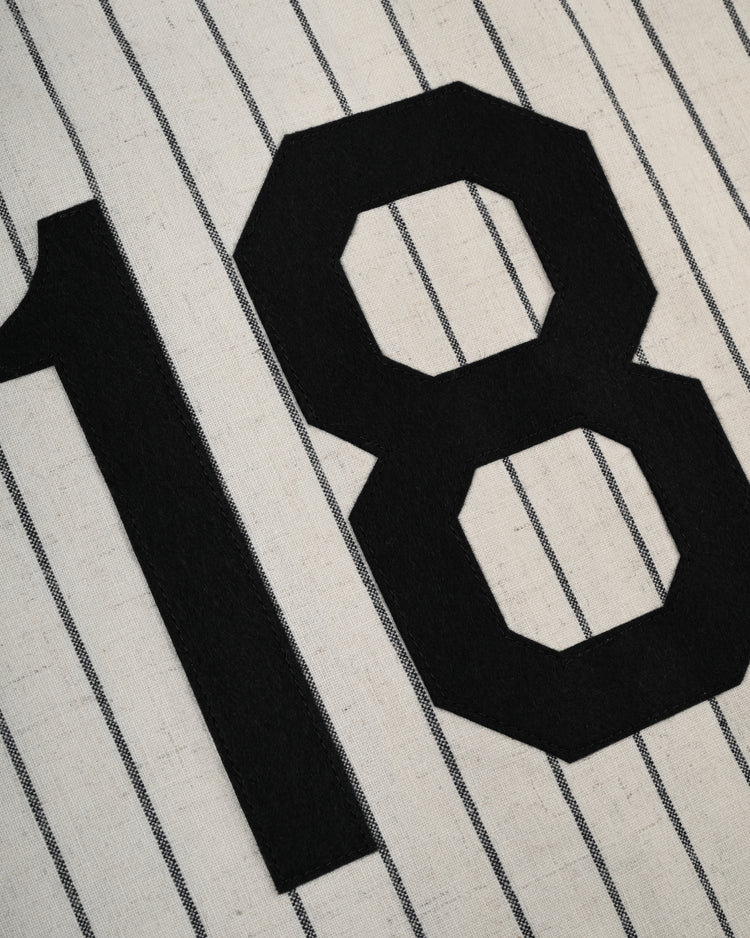 A close-up of the bold black number 18 on white pinstripes, from the Ebbets Field Flannels Homestead Grays 1944 Authentic Wool Home Baseball Jersey, inspired by those displayed at the Negro Leagues Baseball Museum.