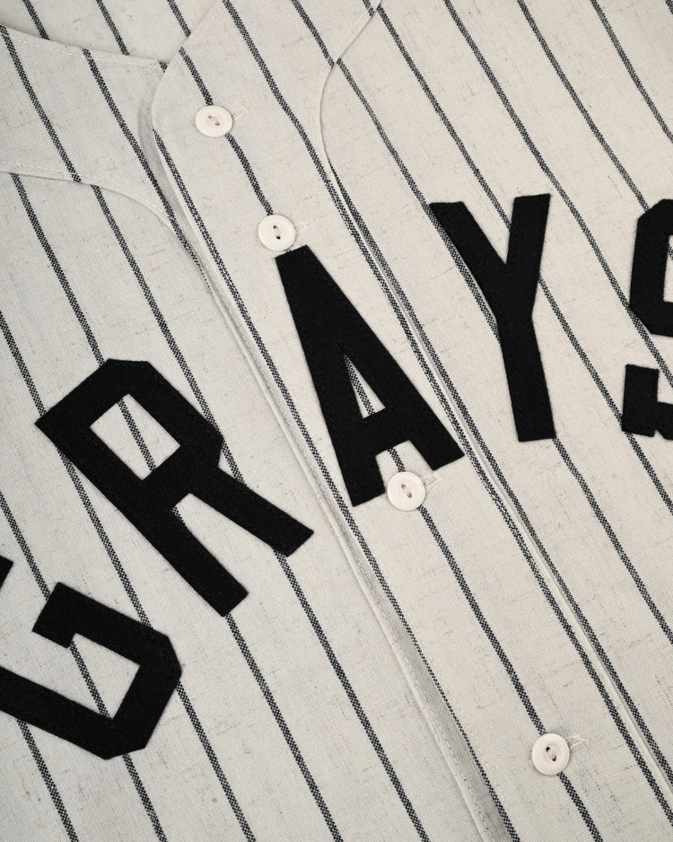 A close-up of the Ebbets Field Flannels Homestead Grays 1944 Authentic Wool Home Baseball Jersey shows thin black pinstripes, bold black GRAYS lettering, and classic white center buttons, echoing Cool Papa Bell’s era.