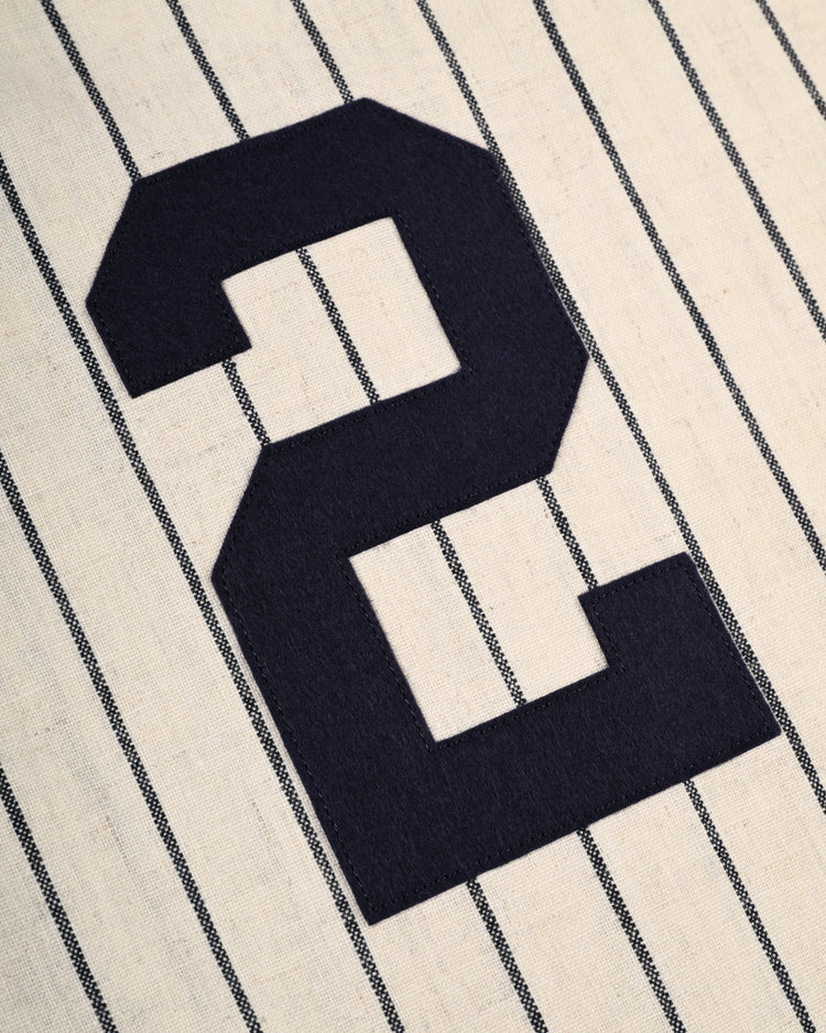 A close-up of a cream-colored pinstriped fabric with a large black number 2 sewn on, from the Ebbets Field Yale University 1948 Authentic Wool Home Baseball Jersey, crafted to replicate classic flannel style.