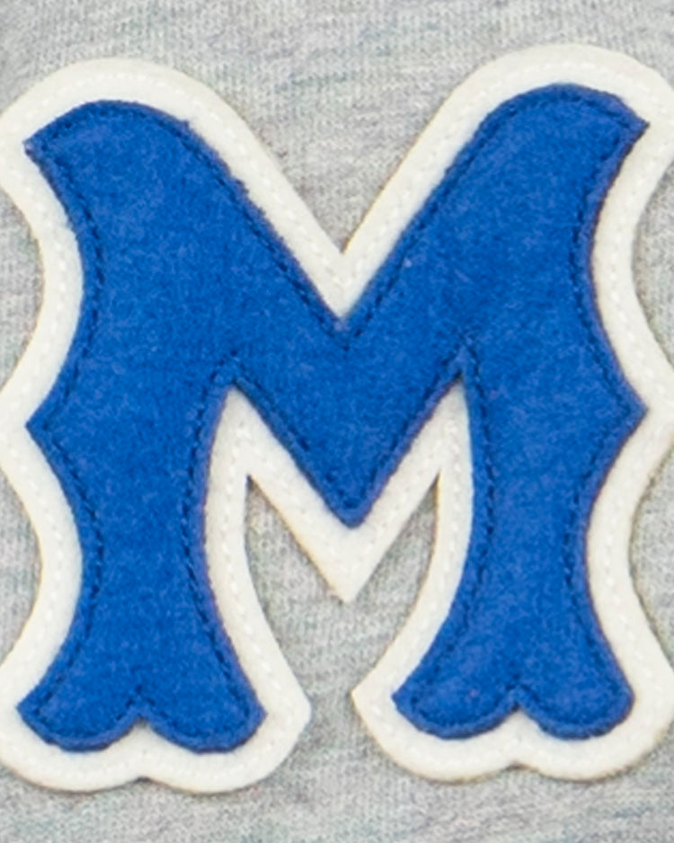 The EFF Montreal Royals French Terry Script Hooded Sweatshirt features a blue letter M with white trim and wavy edges, sewn onto light gray fabric—evoking classic Pittsburgh Pirates and Dodgers prospect styles.