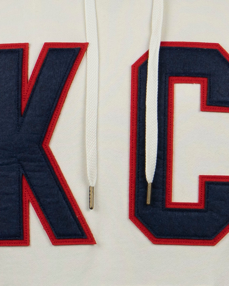 The EFF Kansas City Monarchs French Terry Script Hooded Sweatshirt features large dark blue K and C letters outlined in red, stitched on white fabric with white drawstrings, honoring the Negro Leagues team.
