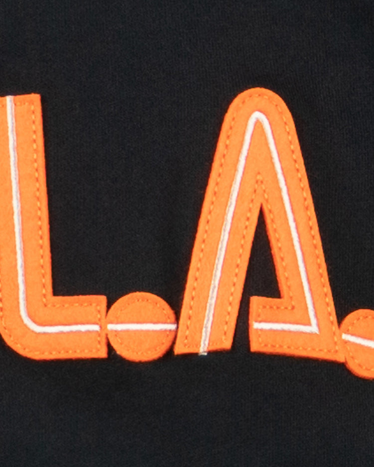 The Los Angeles Aztecs French Terry Script Hooded Sweatshirt by EFF features bold, orange L.A. letters with white accents on black fabric, inspired by the iconic North American Soccer League team where George Best played.
