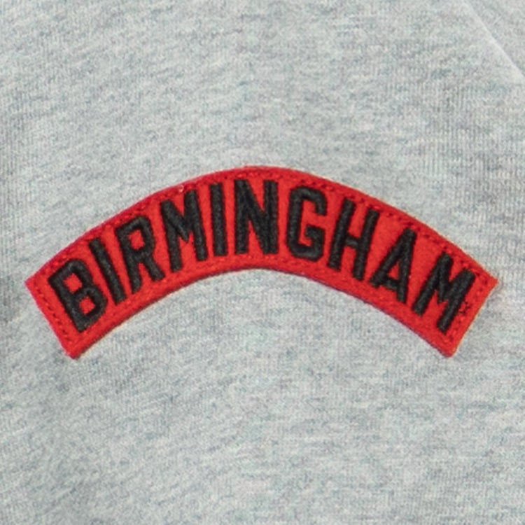 The EFF Birmingham Black Barons French Terry Script Hooded Sweatshirt features a gray fabric with a red patch embroidered with BIRMINGHAM in bold black letters, honoring the legendary Negro National League team.