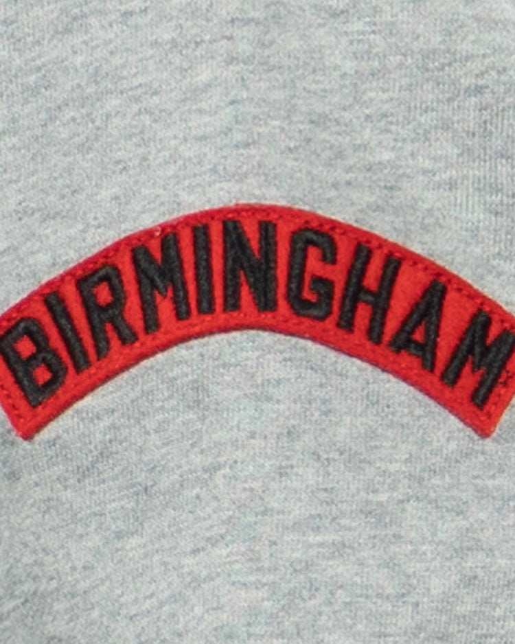 The EFF Birmingham Black Barons French Terry Script Hooded Sweatshirt features a gray fabric with a red patch embroidered with BIRMINGHAM in bold black letters, honoring the legendary Negro National League team.